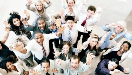 Birds eye view of a happy team looking upwards at the camera with their hands in the air