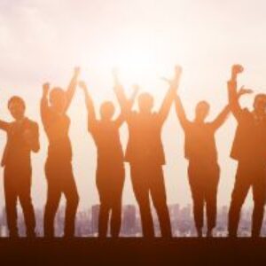 a team of people, mixed genders in silhouette with the sun behind them. All team members have their arms raised, indicating success and happiness