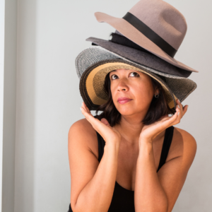 a woman wearing a black vest t-shirt and several hats