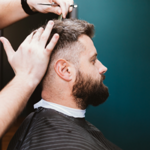 a man sitting in a barber's chair having a haircut