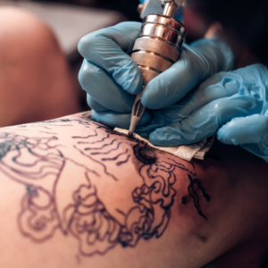 close up shot of a tattoo artists hands on a person's arm, filling in a tattoo