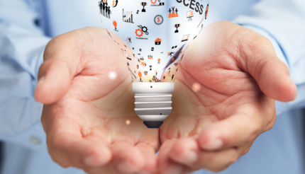 Man holding a stylised lightbulb in the palms of his hands with success on it